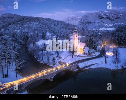 Vue aérienne des montagnes enneigées, église, pont, lumières la nuit Banque D'Images