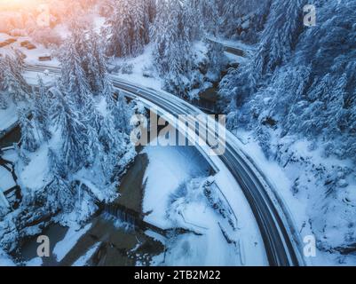 Vue aérienne du pont, rivière, cascade dans la forêt enneigée en hiver Banque D'Images