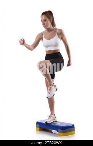 Femme en forme attrayante s'exerçant en studio avec copyspace. Image de jeune athlète féminine en bonne santé faisant de l'entraînement de fitness sur fond blanc. Banque D'Images