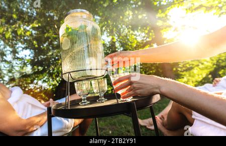 Personne versant de l'eau d'un distributeur de boissons dans un verre à l'extérieur Banque D'Images