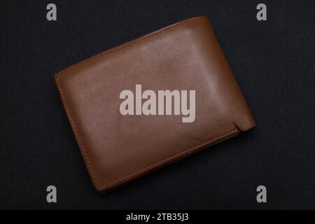 Vue de dessus du nouveau portefeuille en cuir véritable brun isolé sur fond noir. Banque D'Images