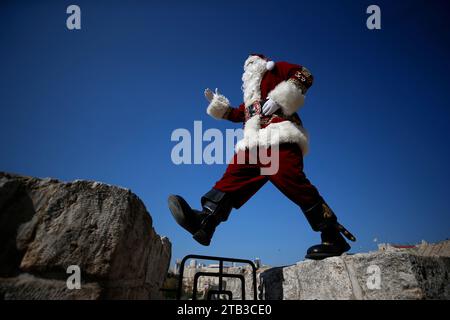 Jérusalem, Israël. 04 décembre 2023. Le palestinien Issa Qassisieh, habillé en Père Noël, pose pour une photo devant les murs de la vieille ville à la porte de Jaffa près du quartier chrétien à Jérusalem-est, quelques semaines avant les prochaines vacances de Noël. Kassissieh, perpétue cette tradition depuis des années. La ville de Jérusalem est considérée comme sacrée dans les croyances musulmanes, juives et chrétiennes. (Photo de Saeed Qaq/SOPA Images/Sipa USA) crédit : SIPA USA/Alamy Live News Banque D'Images