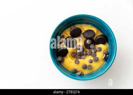 une vue d'oiseau d'un bol d'açai à la mangue surmonté de pépites de chocolat et de biscuits. Banque D'Images