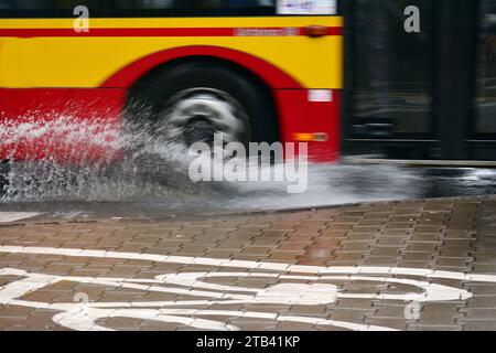 Éclaboussures sous les roues du bus lors de fortes pluies. Bus flou. Banque D'Images