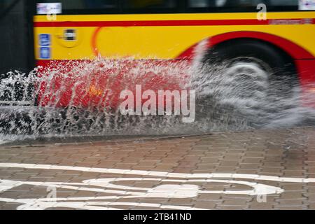Éclaboussures sous les roues du bus lors de fortes pluies. Bus flou. Banque D'Images
