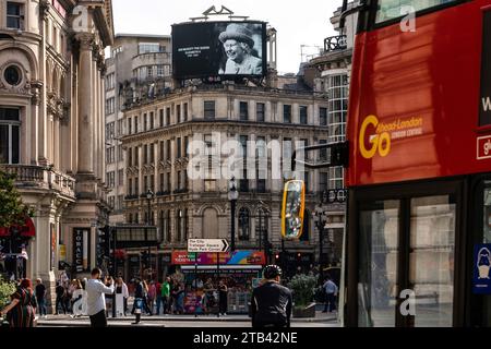 Bus rouge et circulation à Londres avec le portrait de la défunte reine Elizabeth II sur un panneau d'affichage Banque D'Images
