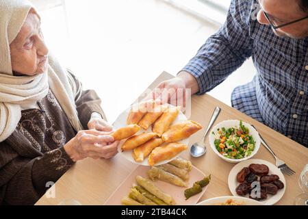 Famille arabe dînant ensemble sur une table en bois avec père, mère, grand-père, grand-mère et fils Banque D'Images