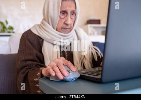 vieille dame utilisant un ordinateur portable dans le salon moderne à des fins en ligne Banque D'Images