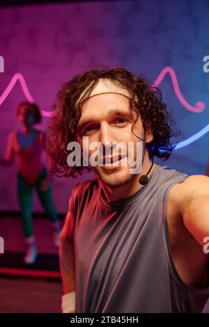 Jeune entraîneur d'aérobic caucasien prenant la photo de lui-même avec la formation de goer de gym sur fond Banque D'Images