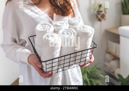 Les mains de la femme mettent ou présentent une serviette blanche enroulée propre en coton biologique. Banque D'Images