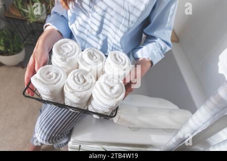 Les mains de la femme mettent ou présentent une serviette blanche enroulée propre en coton biologique. Banque D'Images