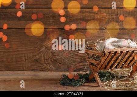 Manger avec mannequin de bébé et foin sur fond en bois. Concept de l'histoire de Noël Banque D'Images