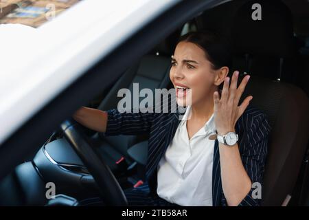 Une conductrice en colère criant dans sa voiture. Coincé dans un embouteillage Banque D'Images