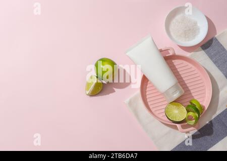 Gros plan d'un tube cosmétique placé sur un plateau en céramique rose avec du citron frais. Le sel de mer est stocké dans un plat en céramique blanche. Espace vide pour l'affichage du produit Banque D'Images