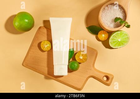 Un tube blanc est placé sur une planche à découper en bois avec kumquat et citron. Le sel de mer est servi dans une cuillère en bois. Étiquettes vierges pour le branding et la publicité Banque D'Images