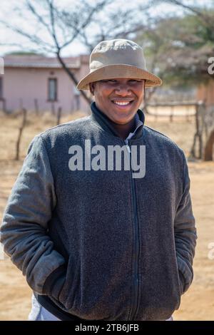villageois , heureux en surpoids jeune homme africain avec un chapeau se promenant dans le canton en milieu d'après-midi Banque D'Images