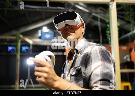 Un jeune homme est engagé avec un casque de réalité virtuelle et des contrôleurs, démontrant la technologie immersive dans un environnement intérieur. Banque D'Images