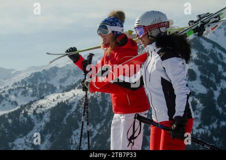 Deux skieurs en équipement de ski coloré souriant et profitant de la vue panoramique sur les Alpes suisses enneigées, prêts pour une journée sur les pistes Banque D'Images