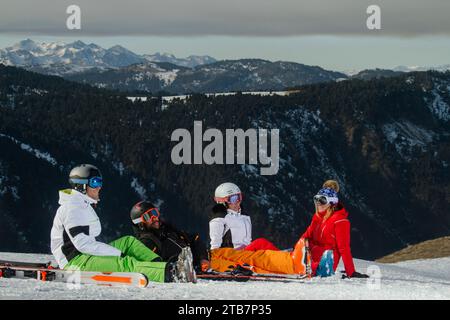 Un joyeux groupe de skieurs en tenues colorées fait une pause sur les pentes enneigées des Alpes suisses, avec des vues sur les montagnes en arrière-plan Banque D'Images