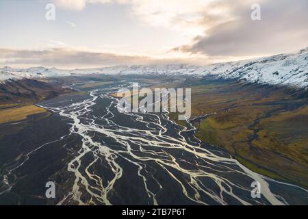 Une prise de vue aérienne captivante capture les motifs complexes des rivières glaciaires serpentant dans la vallée de Thorsmork au milieu des sommets enneigés. Banque D'Images