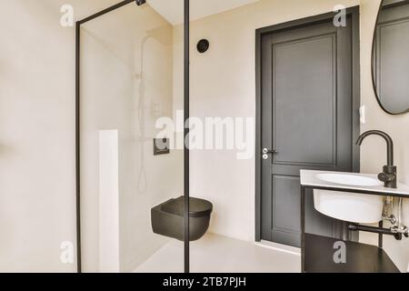 Intérieur de salle de bains spacieuse avec siège de toilette noir et lavabo blanc par douche dans un appartement moderne Banque D'Images
