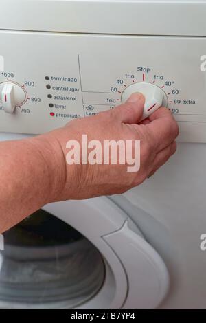 Femme main choisissant le programme sur la machine à laver automatique pour la lessive à la maison. Bouton rotatif du panneau de commande Banque D'Images