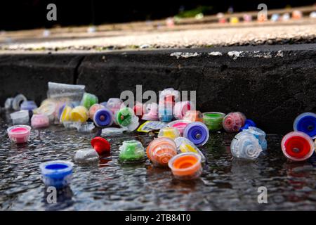 Les bouchons de bouteilles d'eau en plastique multicolores reposent sur une rue mouillée et pavée pendant la course du marathon de Jérusalem. Banque D'Images