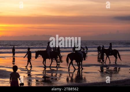 Cavaliers sur la plage de Seminyak au coucher du soleil, île de Bali, Indonésie Banque D'Images
