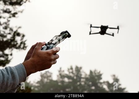 Photographie des mains d'un homme tenant la télécommande d'un Drone (Drone Operator). Concept technologique. l'homme s'amuse avec un quadcopter dans la nature. c Banque D'Images