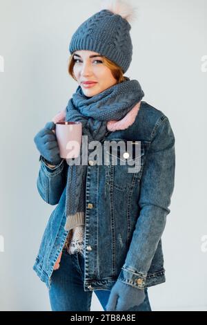 Femme avec un mug en vêtements d'hiver sur un fond blanc Banque D'Images