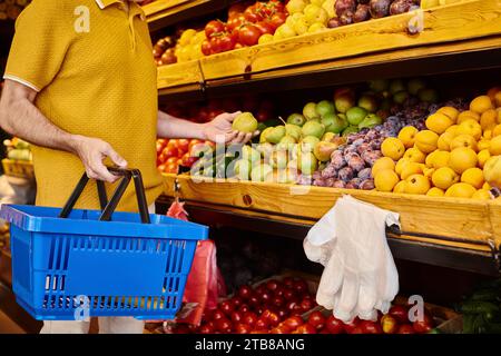 vue recadrée d'un client masculin mature en tenue décontractée cueillant des fruits frais à l'épicerie Banque D'Images