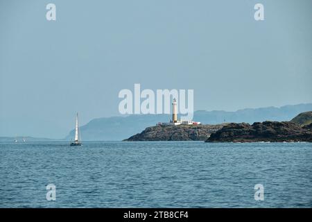 Eilean Musdile, phare de Lismore, entre Oban et l'île de Mull, Hébrides intérieures, Écosse. Voilier au large de la côte Banque D'Images