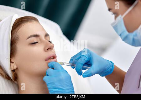 cosmétologue fait des injections pour agrandir les lèvres d'une belle femme. correction de la forme des lèvres Banque D'Images