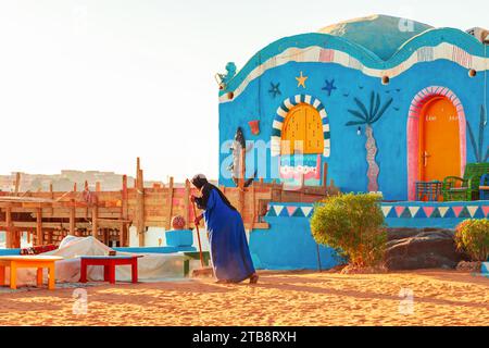 Une femme locale balaie la rue dans un village nubien. Assouan, Égypte – 18 octobre 2023 Banque D'Images