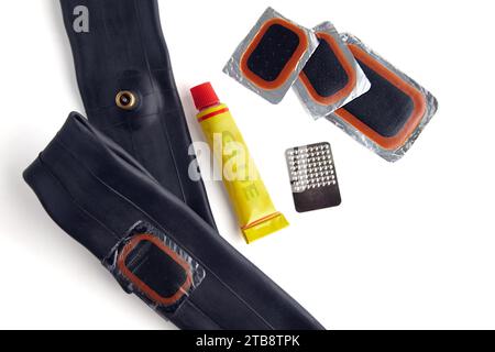 Tube de vélo collé, un ensemble de patchs et un tube de colle isolé sur un fond blanc. Kit de réparation de vélo. Banque D'Images