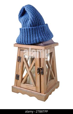 Lanterne de bougie en bois avec un chapeau tricoté bleu sur elle isolé sur un fond blanc. Banque D'Images