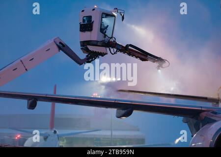 Dégivrage de l'avion avant le vol. Hiver nuit glaciale et service au sol à l'aéroport pendant les chutes de neige. Banque D'Images