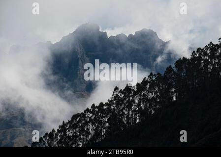 Les nuages enveloppent les montagnes escarpées avec des arbres silhouettés bordant le flanc de la montagne au premier plan, vu de la Vallée sacrée des Incas,... Banque D'Images