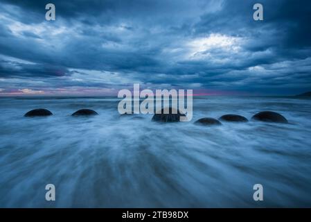 Les vagues se déplacent autour de Moeraki Boulders le long d'un tronçon de Koekohe Beach sur l'île du Sud de la Nouvelle-Zélande ; Hampden, North Otago, Nouvelle-Zélande Banque D'Images