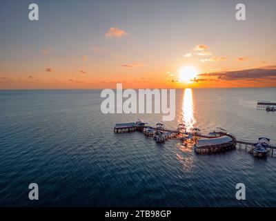 Vue aérienne de coucher de soleil coloré incroyable sur l'océan avec un nuage énorme et silhouette de la jetée Banque D'Images