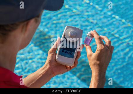 Gros plan d'un technicien de piscine vérifiant le niveau de pH de l'eau avec un compteur numérique Banque D'Images