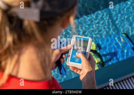 Vue au-dessus de l'épaule d'une personne utilisant une télécommande pour un robot de nettoyage de piscine Banque D'Images