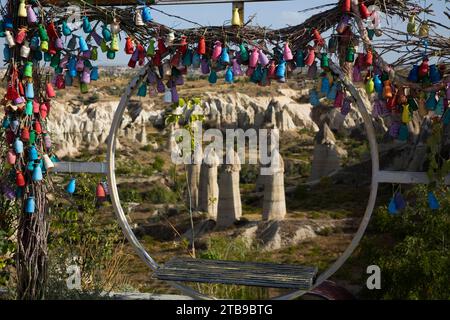 Vue à travers un siège balançoire circulaire décoré de vases en poterie peints en couleurs, des formations rocheuses Fairy Chimney dans Love Valley près de... Banque D'Images