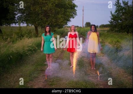 Trois jeunes femmes en vêtements formalwear crackers légers à la campagne ; Bennet, Nebraska, États-Unis d'Amérique Banque D'Images