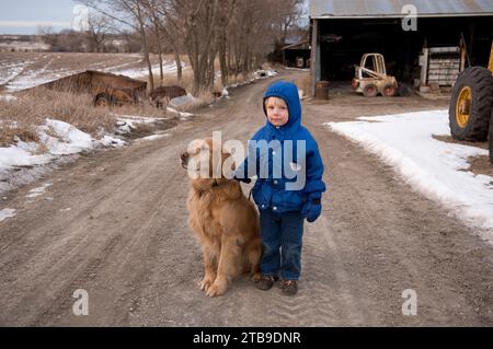 Jeune garçon debout sur une route de gravier avec un Golden retriever ; Cortland, Nebraska, États-Unis d'Amérique Banque D'Images