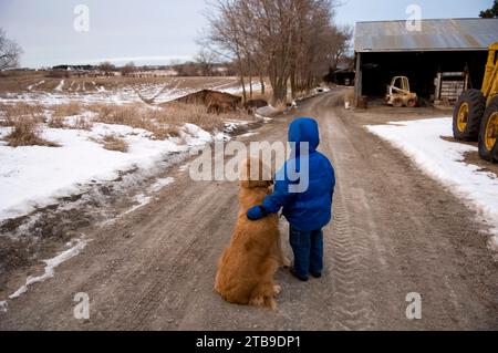 Jeune garçon debout sur une route de gravier avec un Golden retriever ; Cortland, Nebraska, États-Unis d'Amérique Banque D'Images