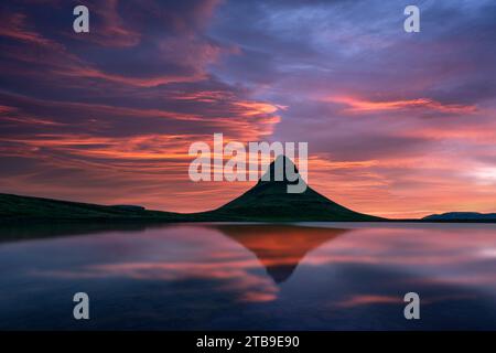 Ciel coloré dramatique au-dessus de la montagne Kirkjufell reflété dans les eaux claires d'un lac de montagne au coucher du soleil. Incroyable scène matinale près de Kirkjufell cascade, Islande. Photographie de paysage Banque D'Images