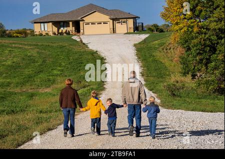 Famille de cinq marchent sur la route de gravier devant leur maison ; Bennet, Nebraska, États-Unis d'Amérique Banque D'Images