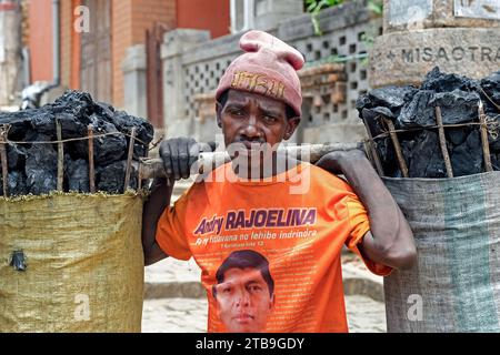 Homme malgache portant de gros sacs de charbon de bois sur ses épaules dans la ville de Fianarantsoa, région de haute Matsiatra, hauts plateaux centraux, Madagascar, Afrique Banque D'Images