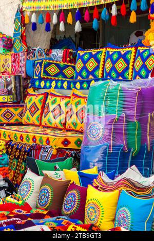 Stand coloré de marché vendant des oreillers et des coussins dans des tissus à motifs traditionnels au Souq Waqif Market place à Doha ; Doha, Qatar Banque D'Images